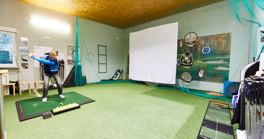 Computergestütztes Golftraining im Indoor-Trainingscenter mit Simulatoren.